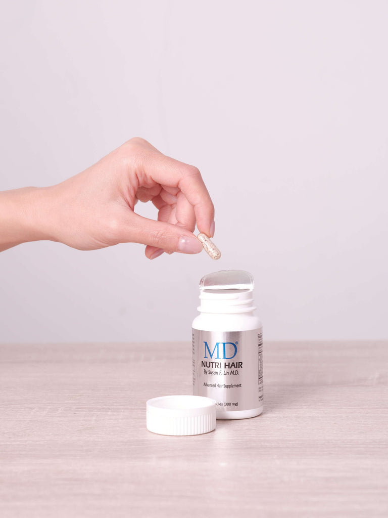 MD Nutri Hair – hand holding small capsule; natural DHT blocker for hair loss, alternative support to Finasteride or Propecia